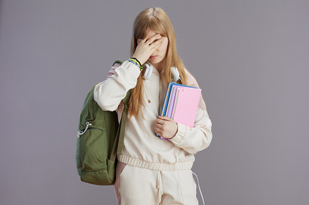 stressed trendy teenager girl in beige tracksuit with backpack, a School & Education Photo by Alliance Images