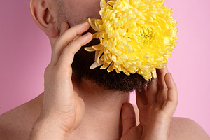 Close-up portrait of a man holding a large yellow chrysanthemum, a Person Photo by Ales Munt