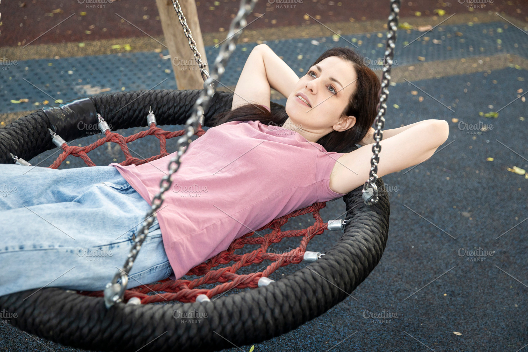 Woman relaxing on a nest swing at a playground, looking up towar, a Person Photo by Imaginarium
