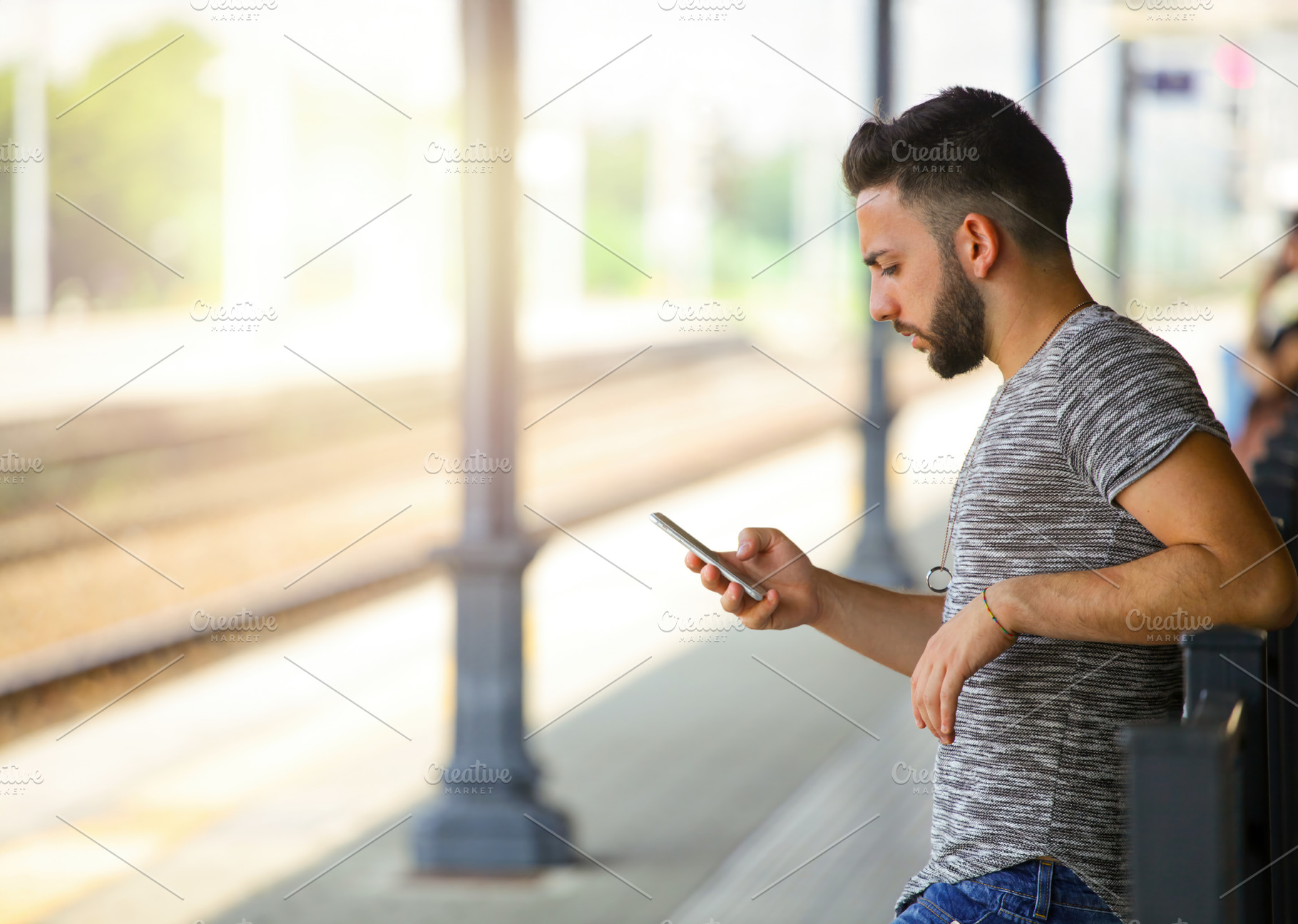 Young man using smartphone while waiting at the train station, an Abstract Photo by Antonio Gravante Market