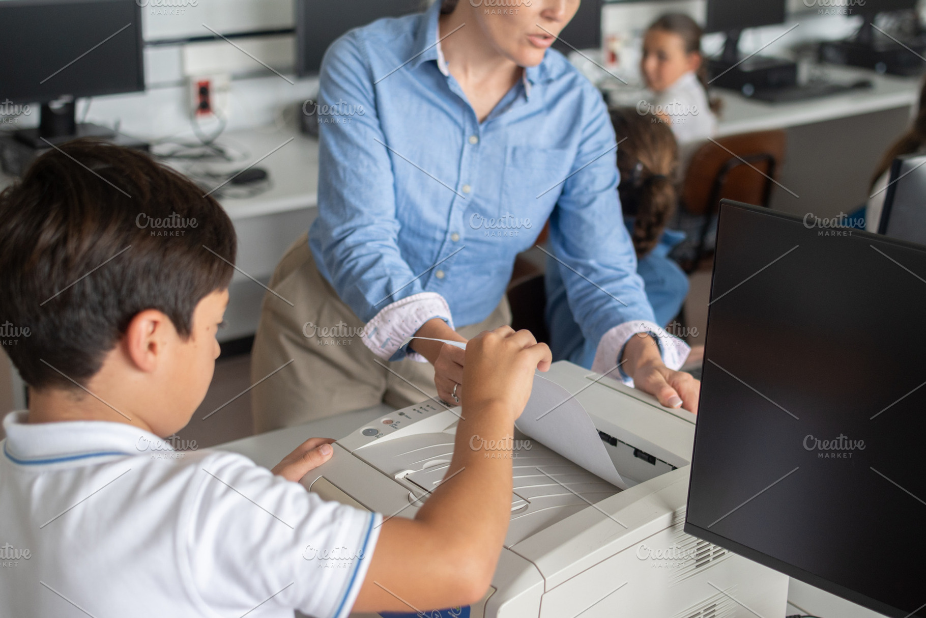 Teacher helping student use printer in school computer classroom, a School & Education Photo by etorres69