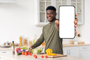 Dieting App. Smiling Young Black Man Holding Blank Smartphone In Kitchen, a Photo by Prostock-Studio