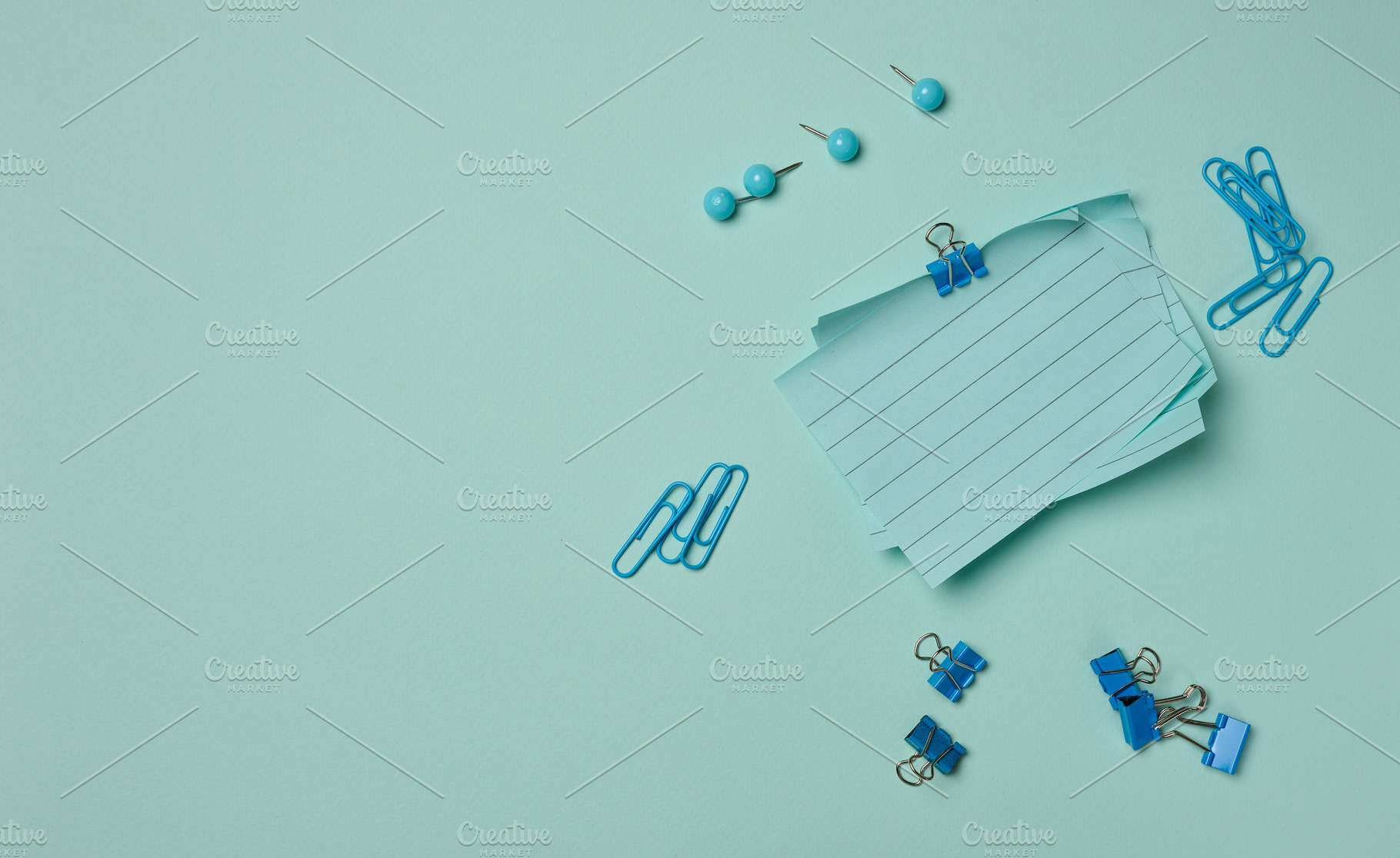 Blue stationery supplies a stack of sheets, paper clips, and pus, a Business Photo by ndanko