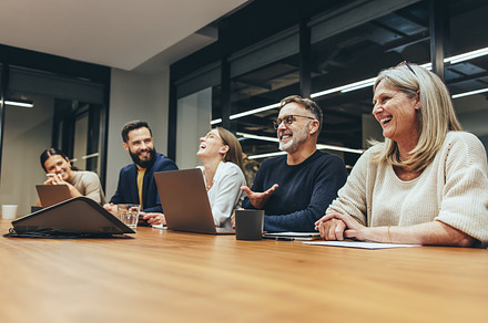 Cheerful businesspeople laughing during a meeting, a Person Photo by Jacob Lund
