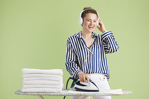 Woman listening to music while ironing towels, a Person Photo by Alliance Images