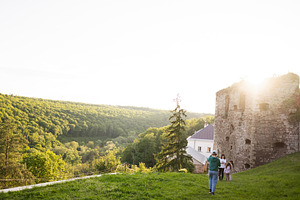 Family walking near ancient ruins in a lush green countryside during sunset, a Person Photo by AS photostudio