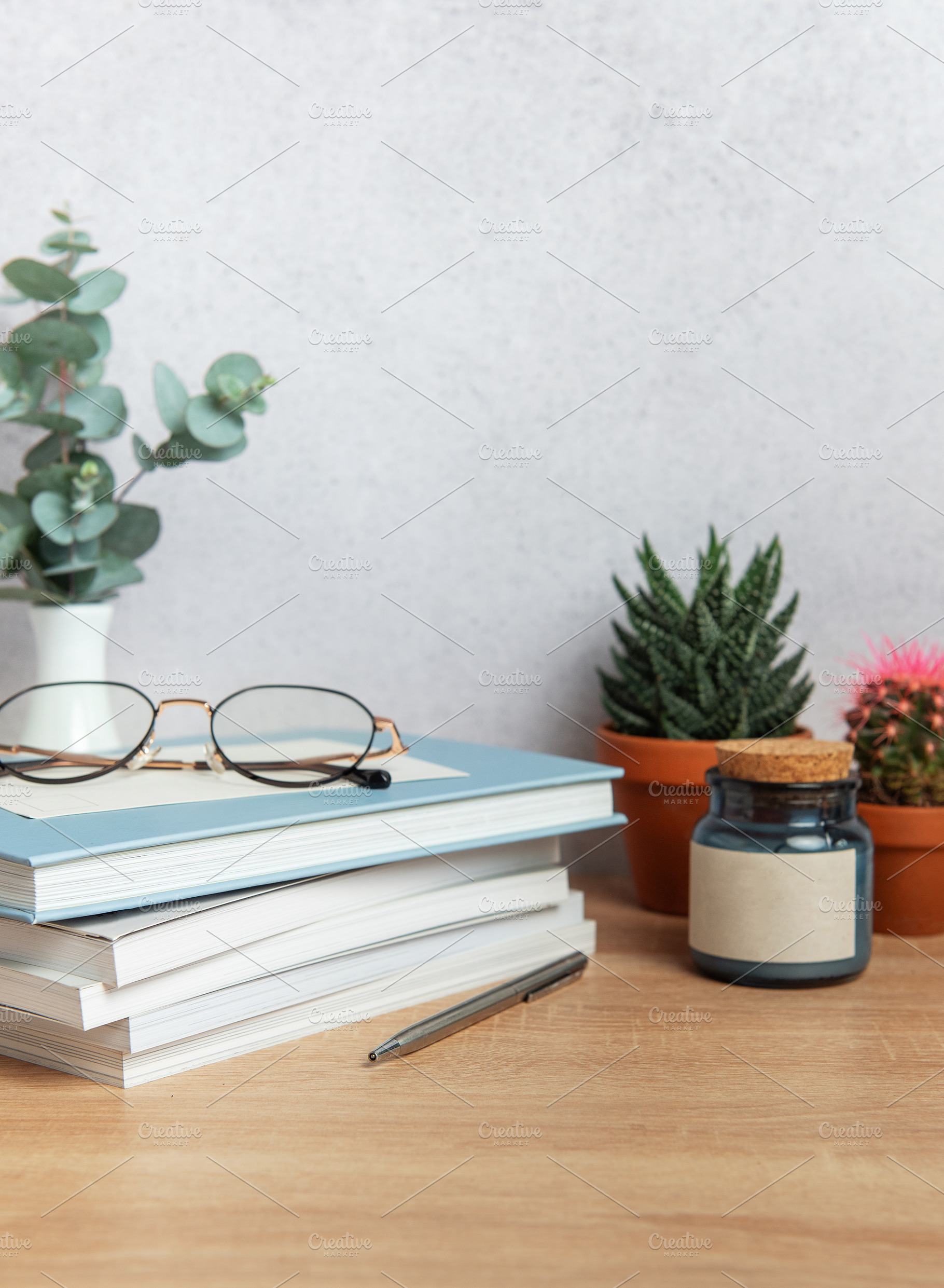 Eyeglasses resting on stack of books with plants and pen on wood, a Business Photo by Olena Rudo