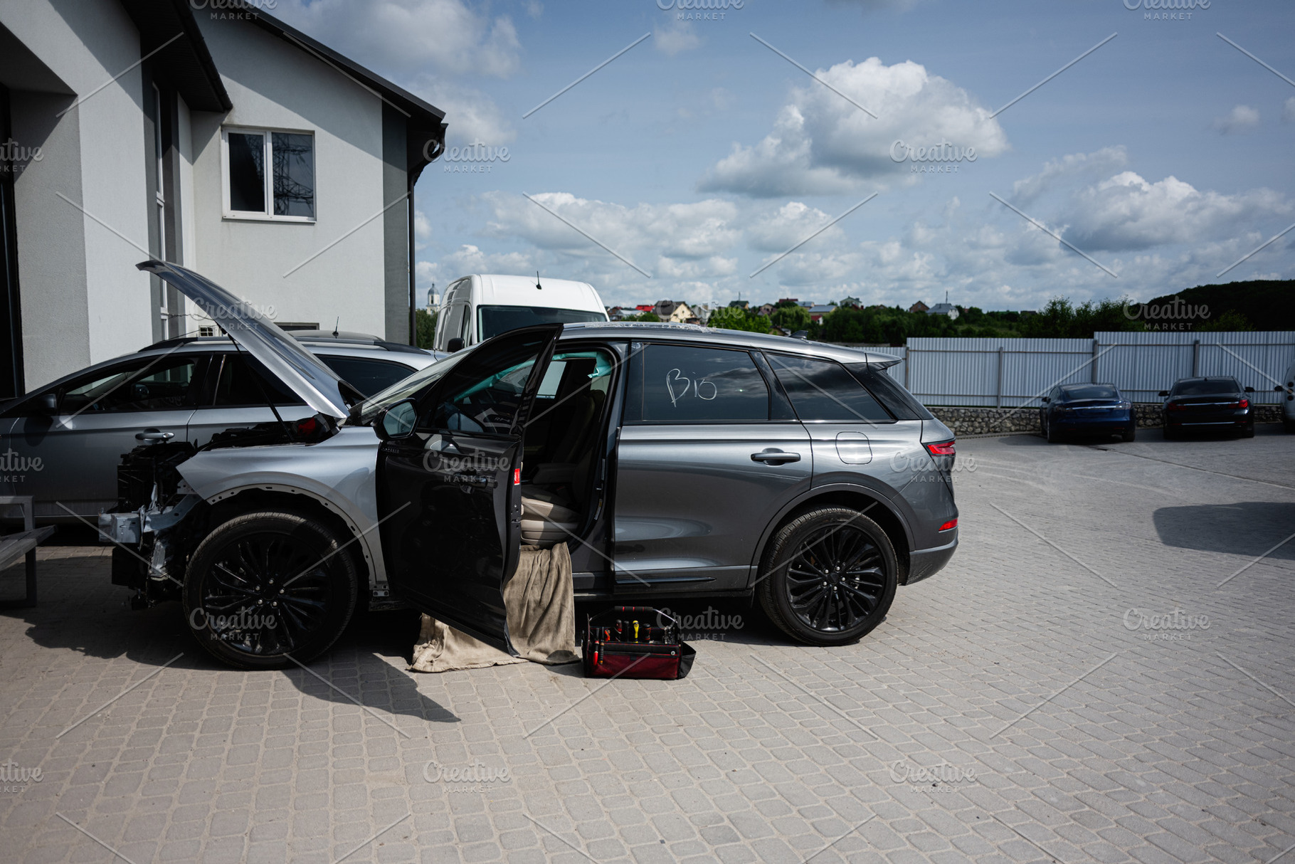 Modern silver car under repair outdoors with tools and open hood, a Transportation Photo by AS photostudio
