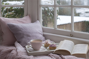 Cozy winter window seat with tea, cupcakes, and a book, creating, a Photo by Studio ANNA
