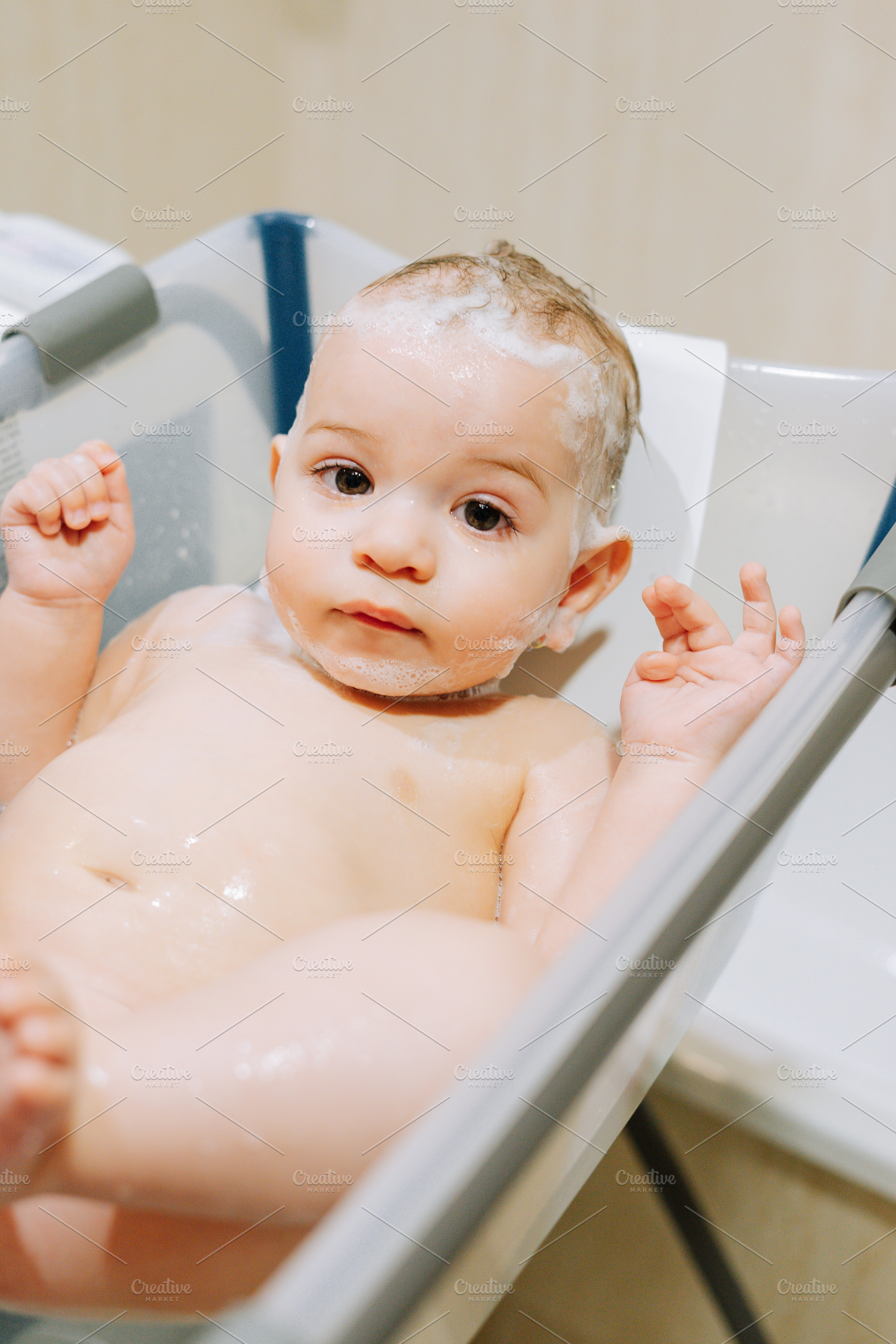 Portrait of a nine month old baby taking a bath in a baby bathtub, a Person Photo by rubenchase