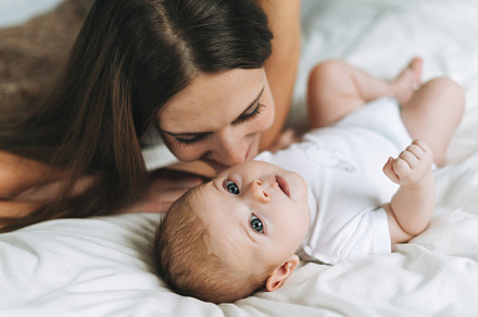 Young mother with baby girl on bed, a Person Photo by Galina_Zhigalova