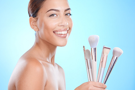 Cosmetic, makeup brushes and portrait of a woman in a studio for a beauty, natural and face routine. Cosmetics, skincare and female model from Brazil with a facial glow isolated by a blue background., a Photo by Peopleimages.com