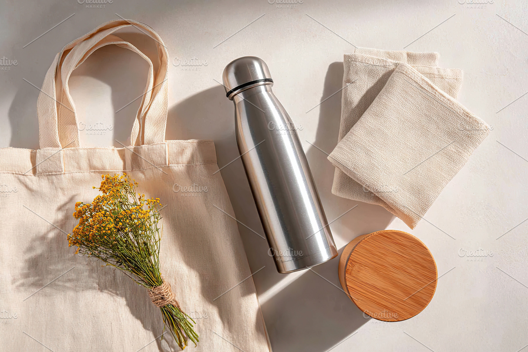 Stylish reusable items for sustainable living featuring a water bottle and tote, a Photo by AlyaAnd