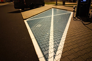 Night scene of electric vehicle charging station in Poland with blue paving and, a Photo by AS photostudio