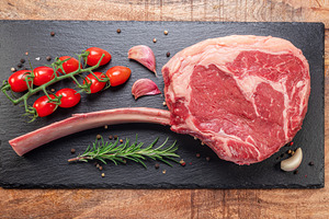 Raw rib steak with bone or tomahawk steak with seasonings on sla, a Food & Drink Photo by Volff