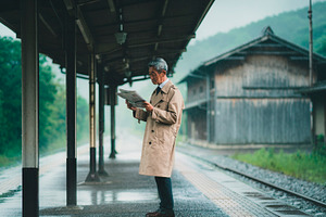 Asian senior traveler reading train departure information on a s