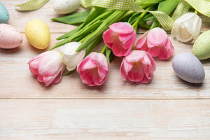 Easter eggs and pink tulips resting on white wooden table, a Holiday Photo by Olena Rudo
