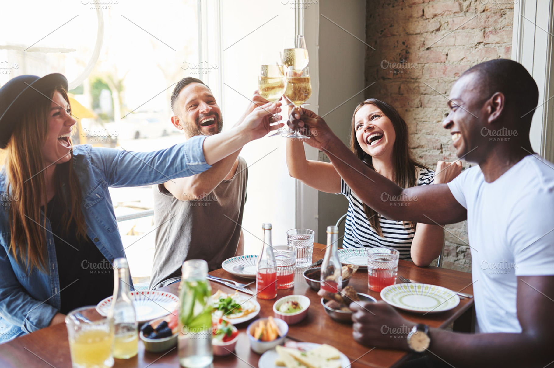 Group of four laughing adults toasting drinks, a Person Photo by Stefan & Janni