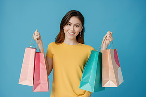 Young smiling woman holding colorful paper shopping bags, a Person Photo by AlyaAnd