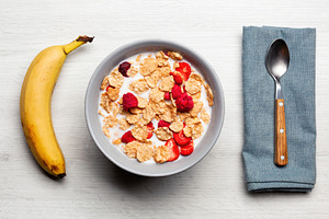 Healthy breakfast with cereals, milk, strawberries, raspberries and banana on w, a Food & Drink Photo by Antonio Gravante Market