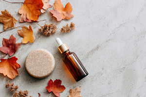 Skincare product mockup with autumn leaves on stone surface in soft natural lig, a Beauty & Fashion Photo by AlyaAnd