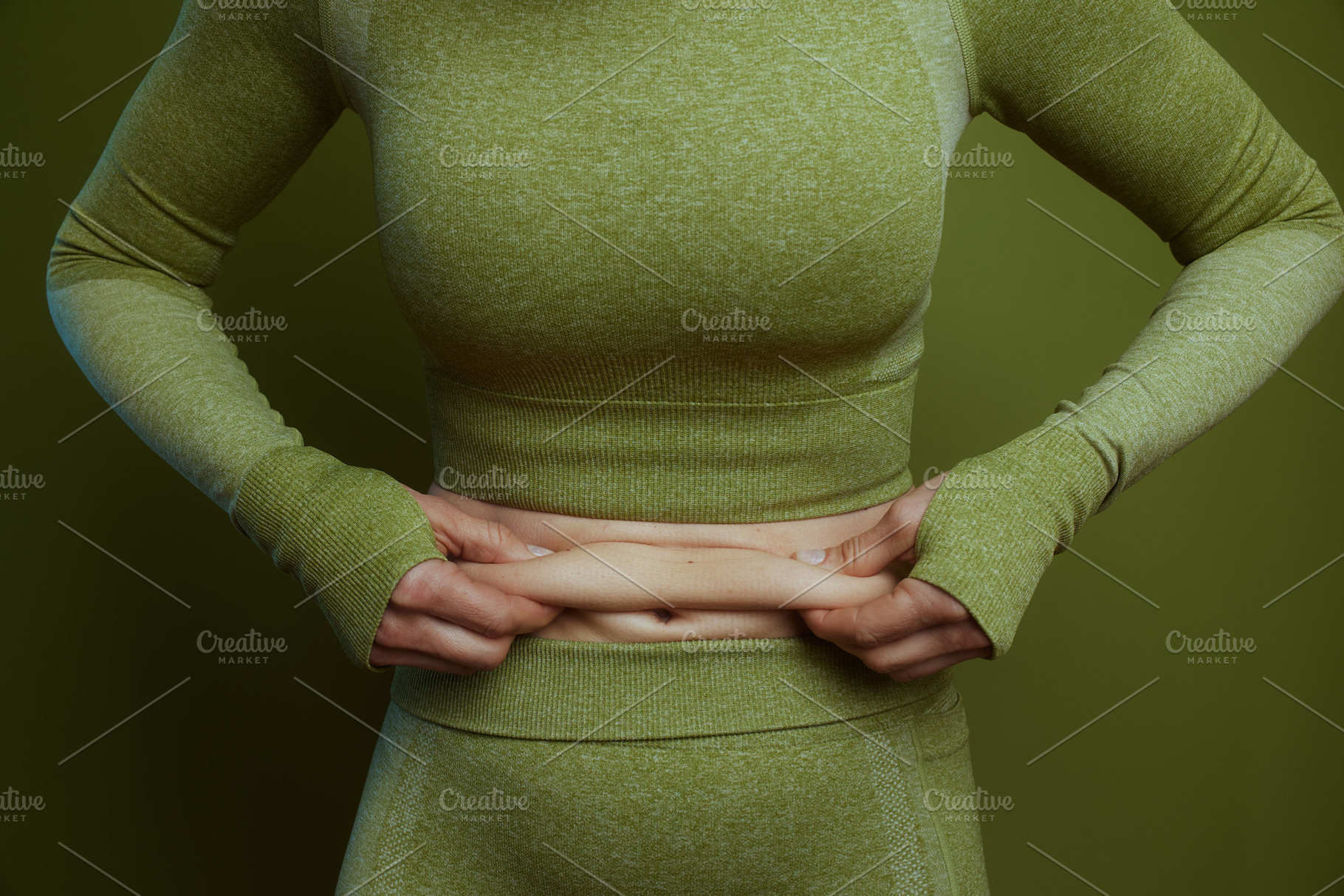Woman in green activewear pinching belly skin, a Person Photo by Alliance Images