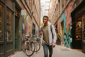 Black teenager walking through colorful downtown alley, a Person Photo by DanFLCreativo