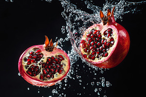 Fresh pomegranate falling in transparent water, a Food & Drink Photo by AlyaAnd