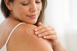 Woman applying lotion on shoulder fo, a Photo by Dvoevnore photos