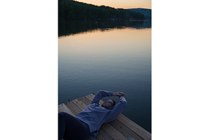 Woman lying down on the pier at lake, a Person Photo by Jan Jack Russo Media