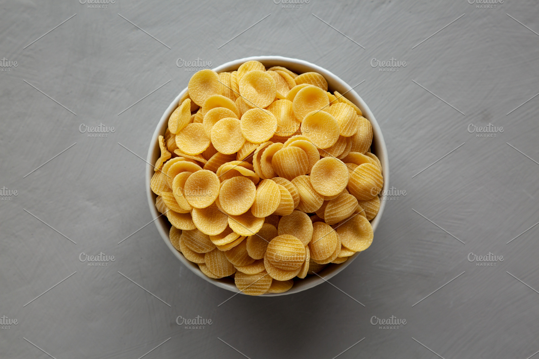 Dry, Uncooked Orecchiette Pasta in a Bowl, top view. Flat lay, o, a Food & Drink Photo by LiudmylaChuhunova