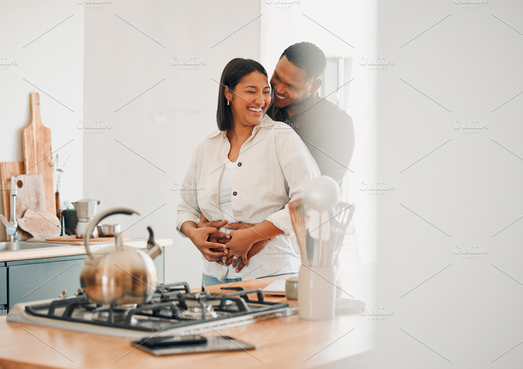 Loving, happy and hugging couple relaxing in the kitchen at home smiling and laughing together. Carefree, excited and affectionate lovers having fun and enjoying quality time in the house, a Photo by Peopleimages.com