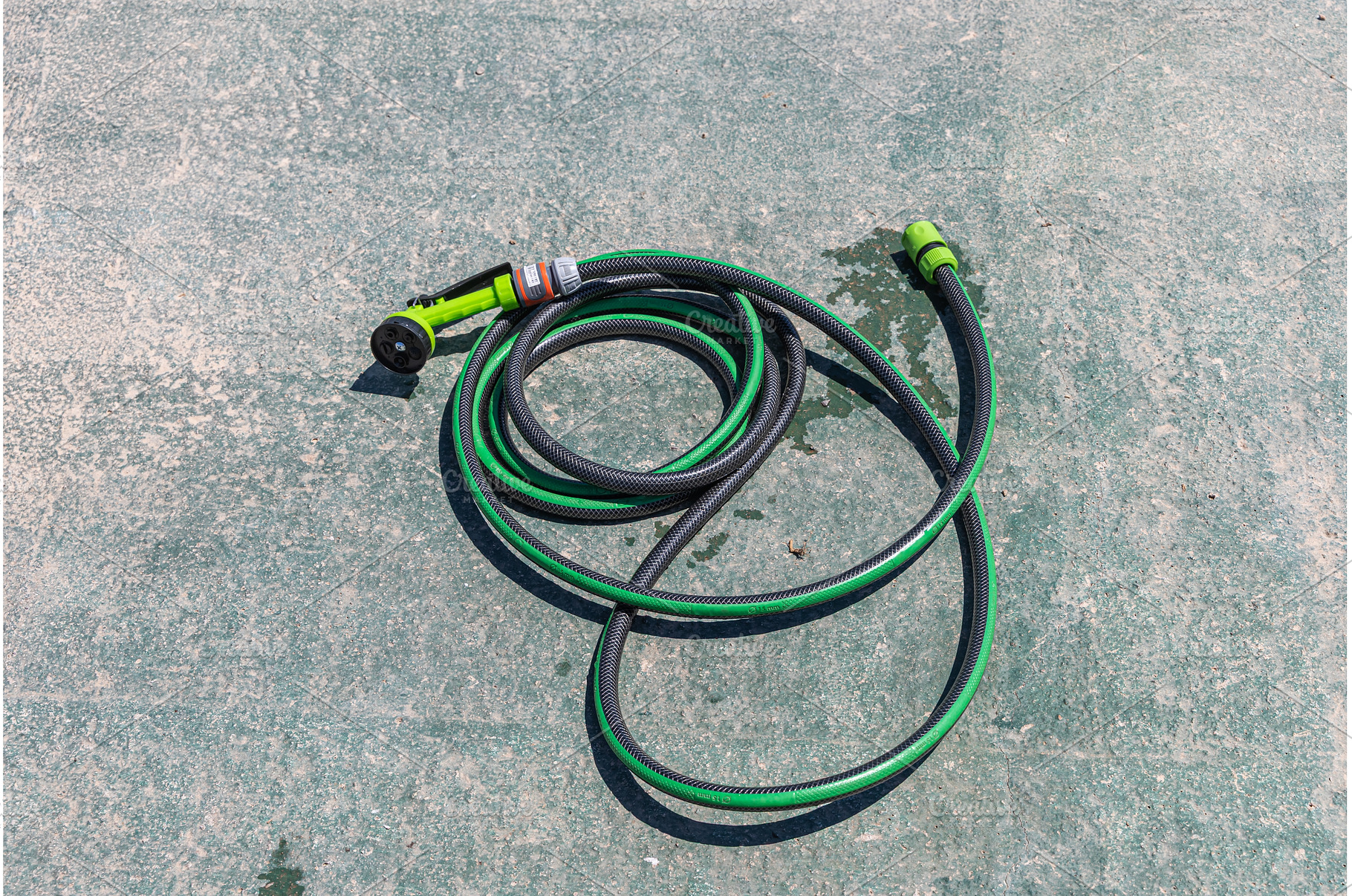 Green garden hose with spray nozzle, an Industrial Photo by Illustrations&photos