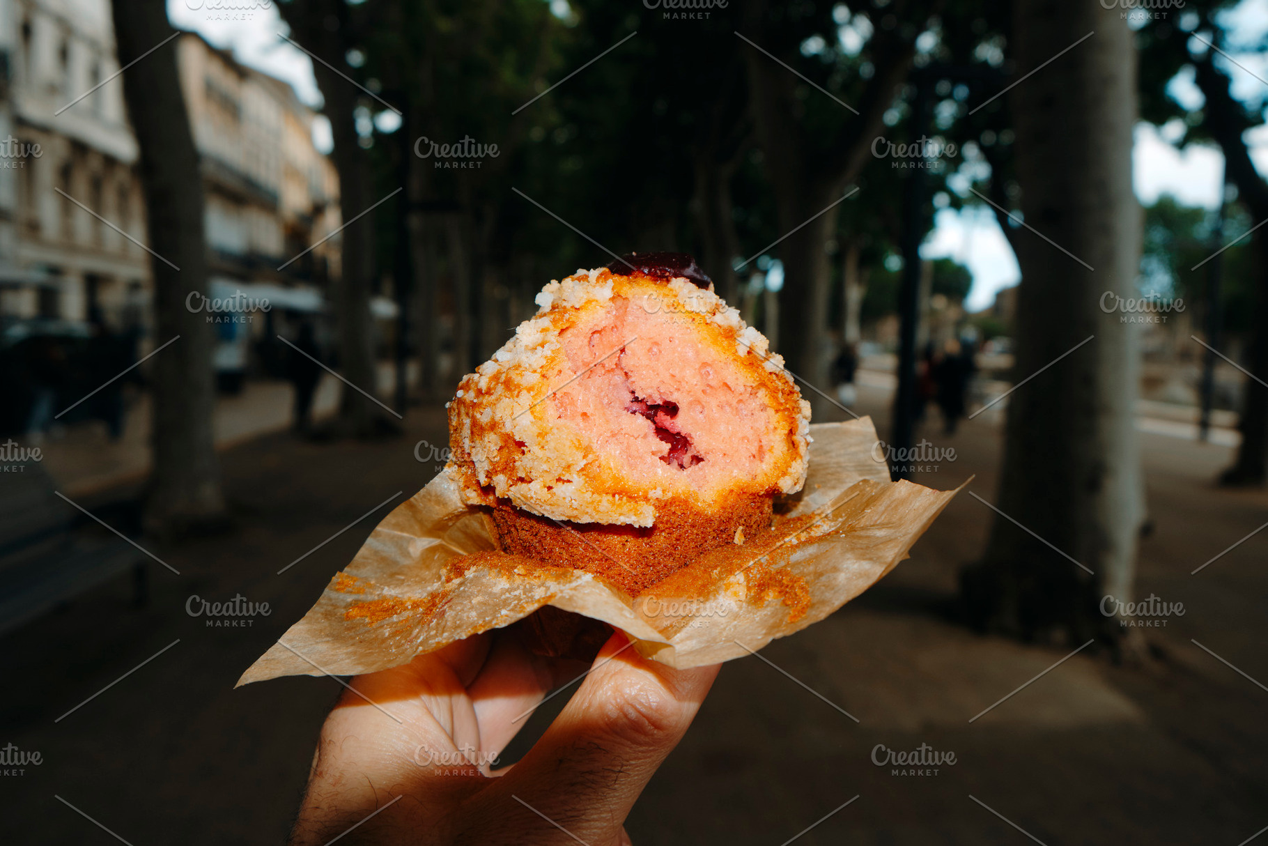 man eating a muffin filled with strawberry jam, a Photo by Nito