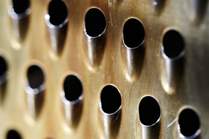 Close-up of a rustic kitchen tool with rhythmic perforated holes. Macro of oxid, a Background Photo by Rohan Photography