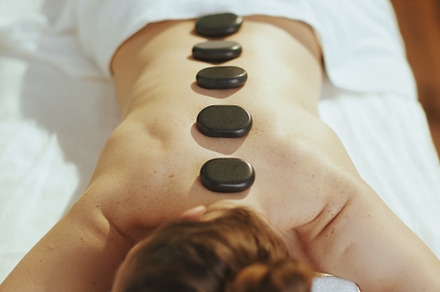 woman having hot stone massage and laying on massage table, a Person Photo by Alliance Images