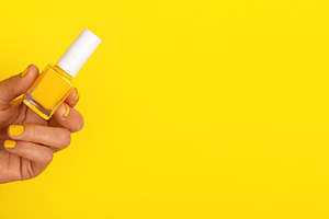 Close-up of a hand with yellow polished nails holding a yellow n, a Beauty & Fashion Photo by Ales Munt