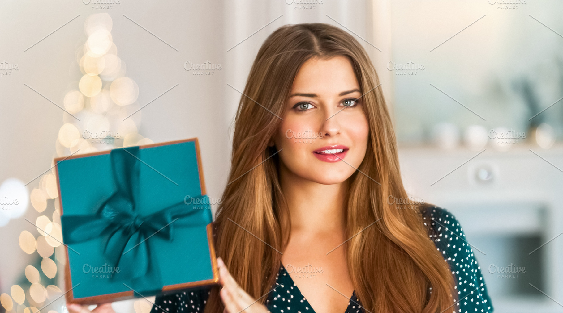 Young woman smiling, holding a teal gift box with a ribbon, cele, a Person Photo by Studio ANNA