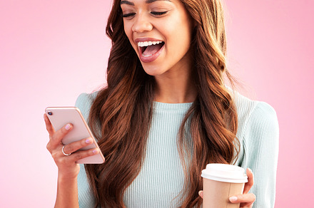 Phone, coffee and woman laughing in studio isolated on a pink background. Tea, cellphone and happy mixed race female with smartphone for social media, funny meme or comic joke, web browsing and text., a Photo by Peopleimages.com