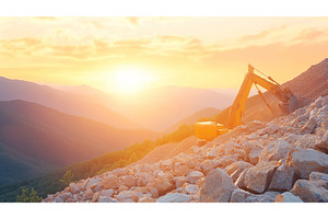 Excavator working at sunset on rocky, an Industrial Photo by Lermont51