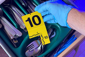 Investigator handling evidence marker at crime scene drawer
