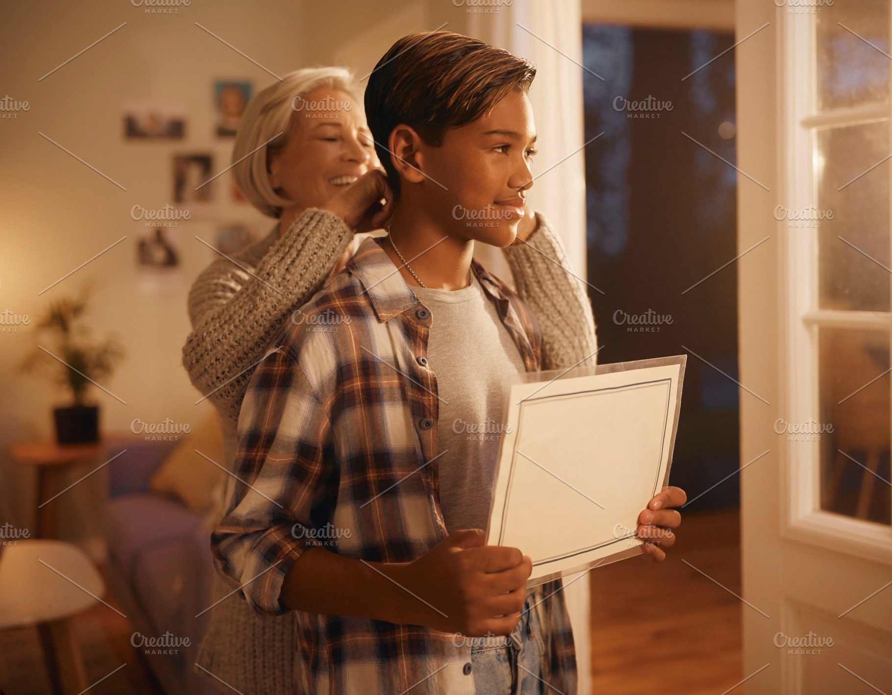 Young man holding blank sign while mother puts necklace, a Photo by DanFLCreativo