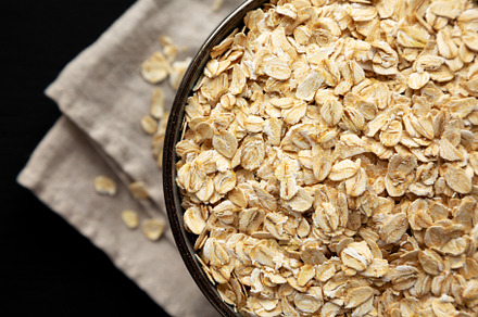 Wholegrain Oat Flakes in a Bowl on a black background, top view., a Food & Drink Photo by LiudmylaChuhunova