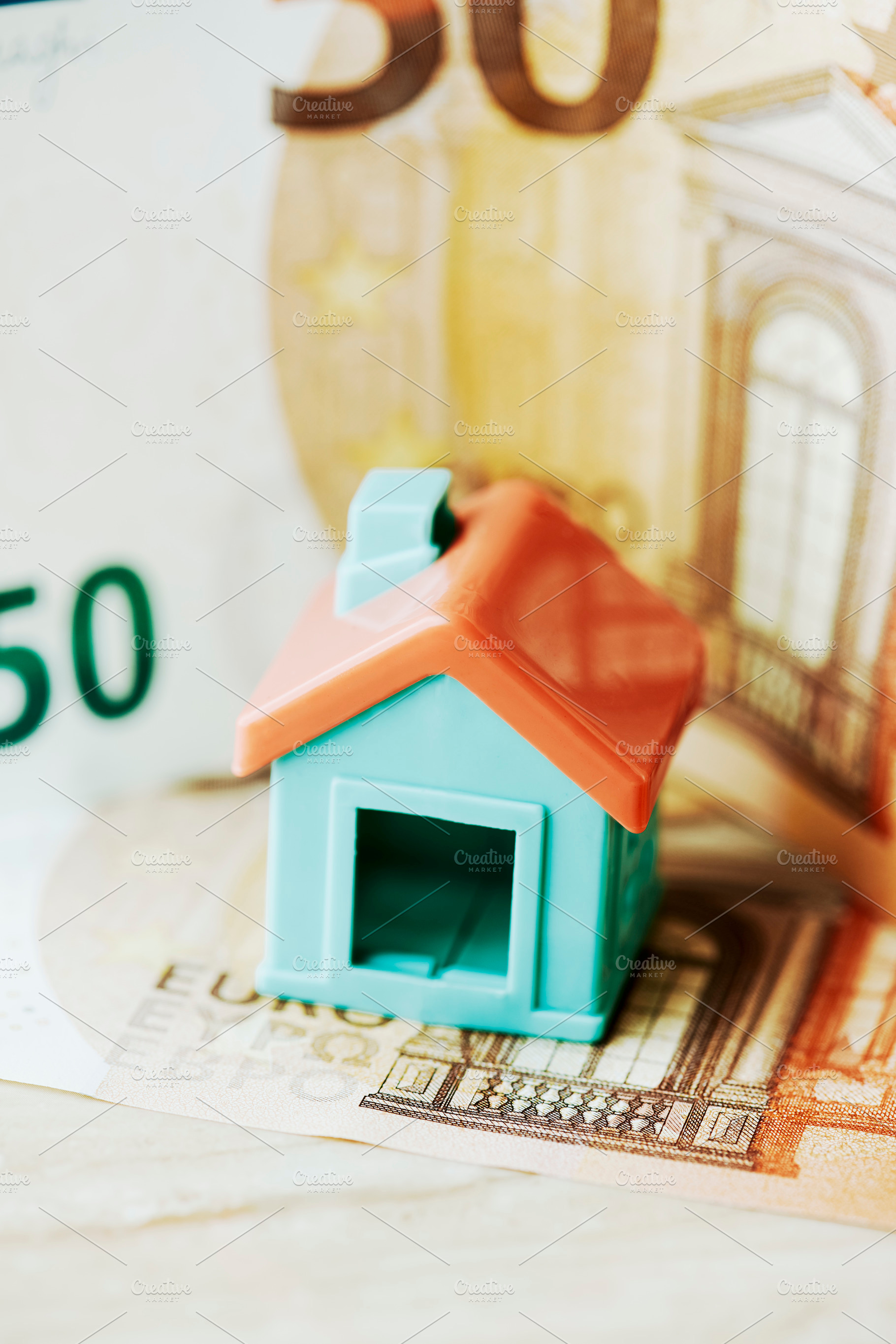 a toy house placed over a euro banknote, a Photo by Nito