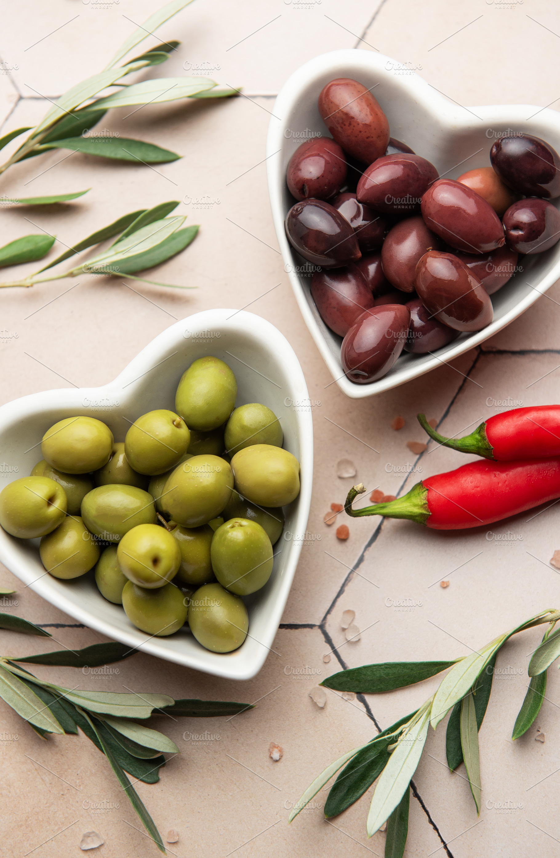 Heart shaped bowls containing green and black olives, olive bran, a Food & Drink Photo by Olena Rudo