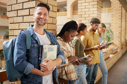 University, hallway and portrait of man and students standing in row together with books and tablet before class. Friends, education and future, happy man in study group on campus in lobby for exam., a Photo by Peopleimages.com