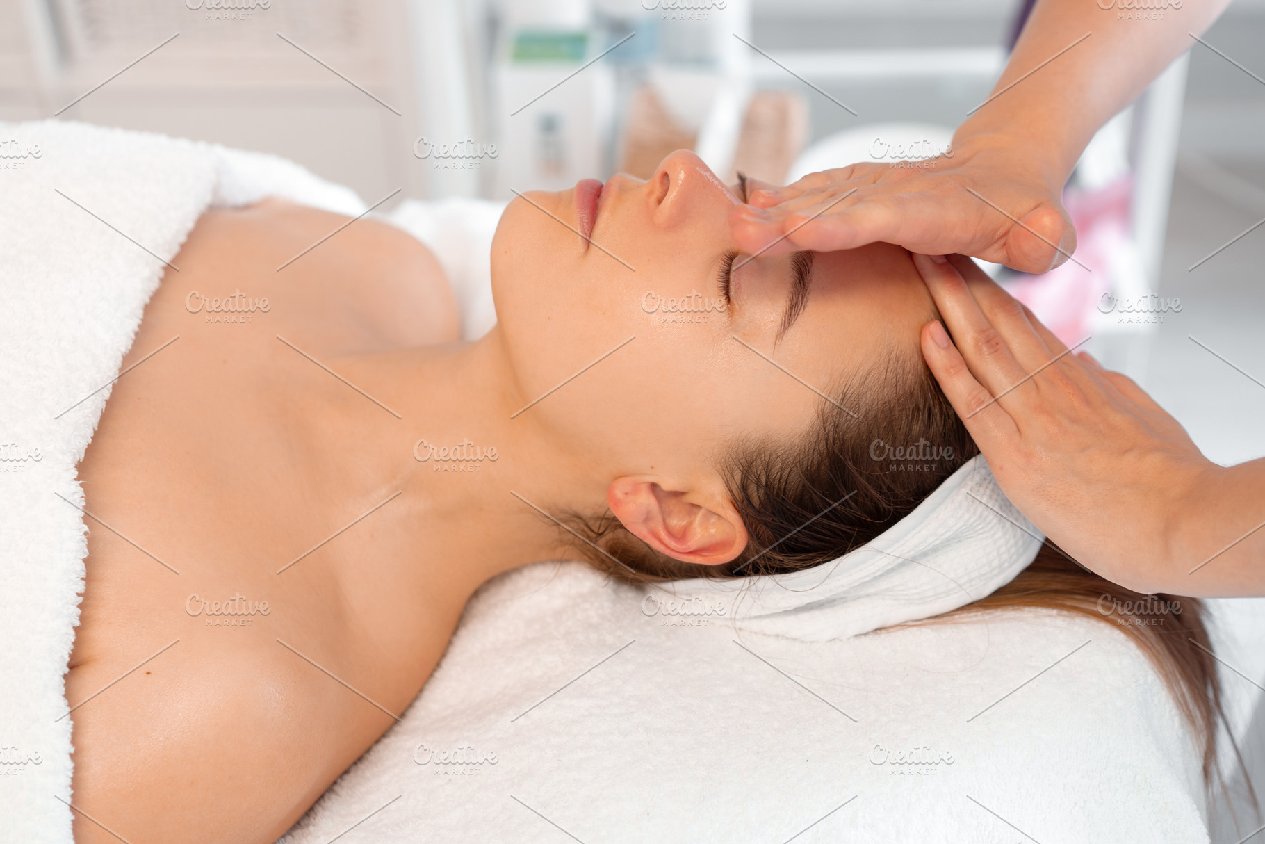 Crop massage therapist massaging woman's forehead at cosmetology spa, a Photo by andreonegin market