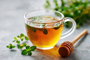 Steaming cup of tea with mint leafs on a table, a Food & Drink Photo by AlyaAnd
