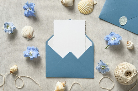 Blue envelope with wedding invitation card mockup inside, seashells, flowers to, a Holiday Photo by photoguns