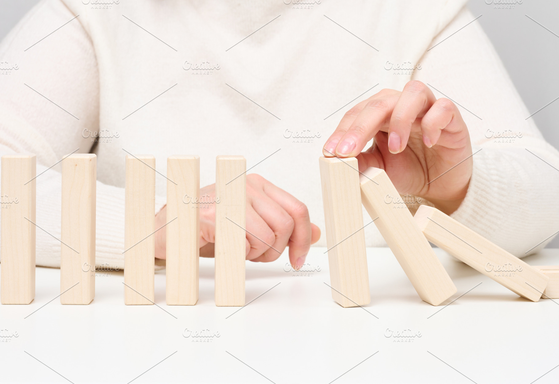 Woman's hand stopping falling wooden blocks, preventing the domi, a Person Photo by ndanko
